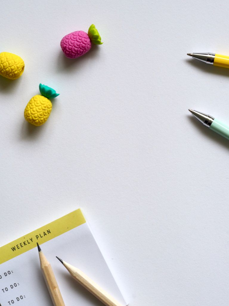 Flat lay of colorful stationery including pens, pencils, erasers on a white background.